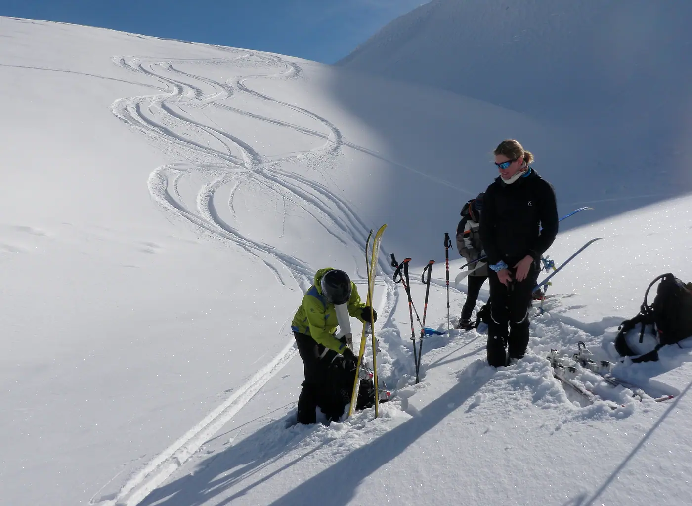 Zwei Tourengeher fellen im Pulverschnee ab, im Hang dahinter ihre Spuren